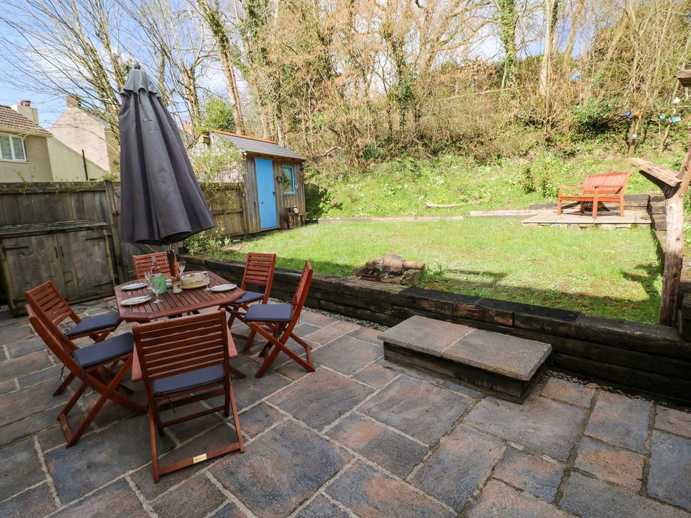 A garden with a table, chairs, and shed at 1 Mill Farm Cottages in Narberth