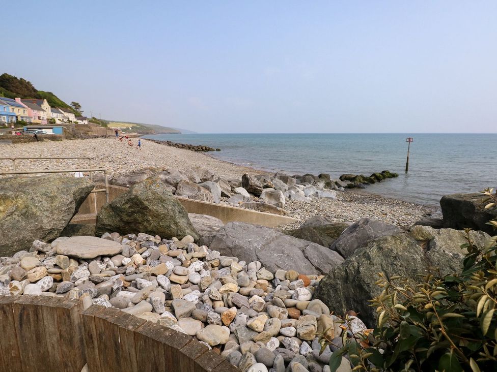 A beach with rocks and houses along the shoreline at 1 Mill Farm Cottages in Narberth
