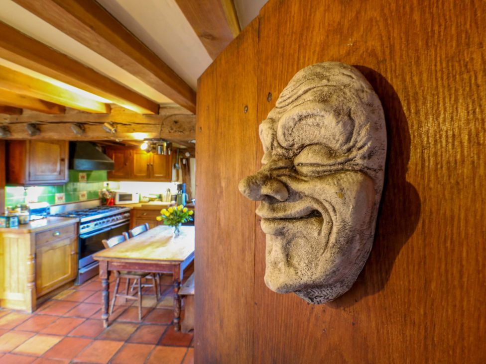 A kitchen with a wooden table and decorative mask at Town Farm 