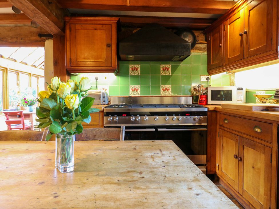 A kitchen with a stove, microwave, and flowers on a table at Town Farm
