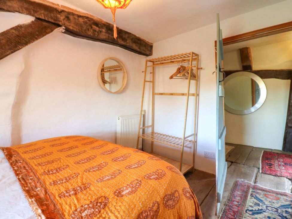 A bedroom with a quilted bed and a clothes rack at Town Farm in 