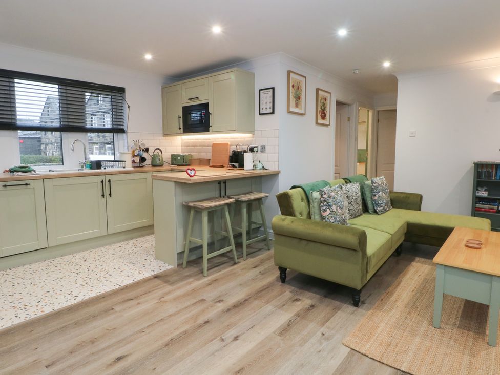 A living room with a sofa and kitchen area at 4 Downshutts Lane Holmfirth