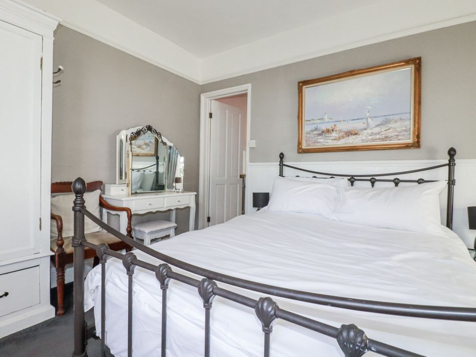 A bedroom with a bed, mirrors, a wardrobe, and a painting at Rosedale in St. Ives