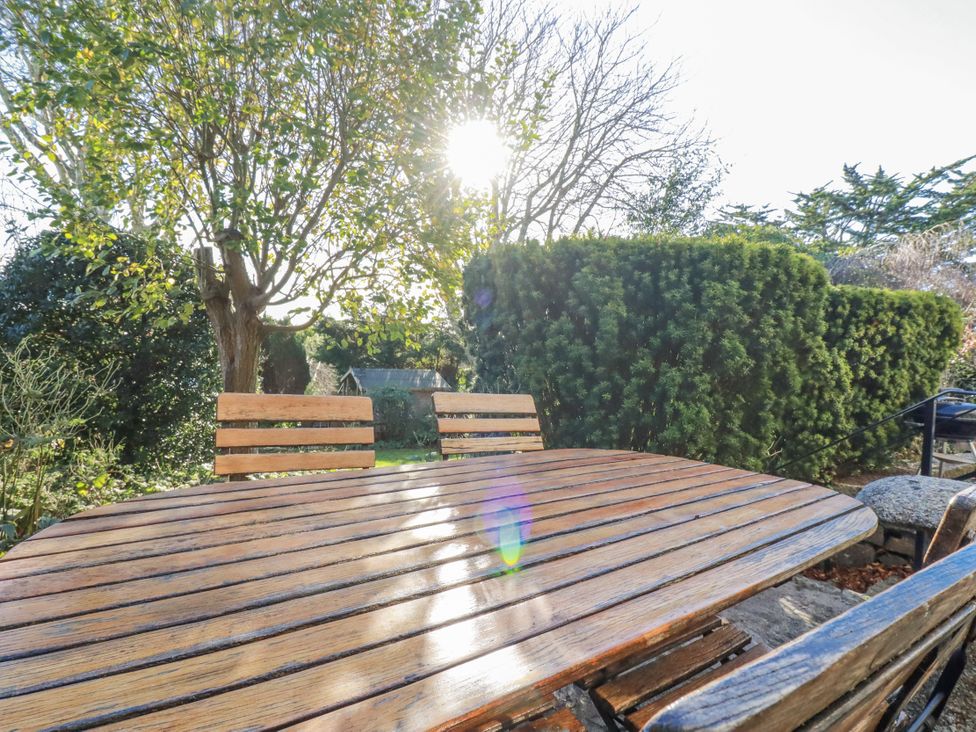 A garden with a wooden table and chairs at Rosedale in St. Ives