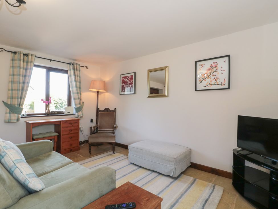 A living room with a sofa, armchair, and television at The Cowshed in Bristol