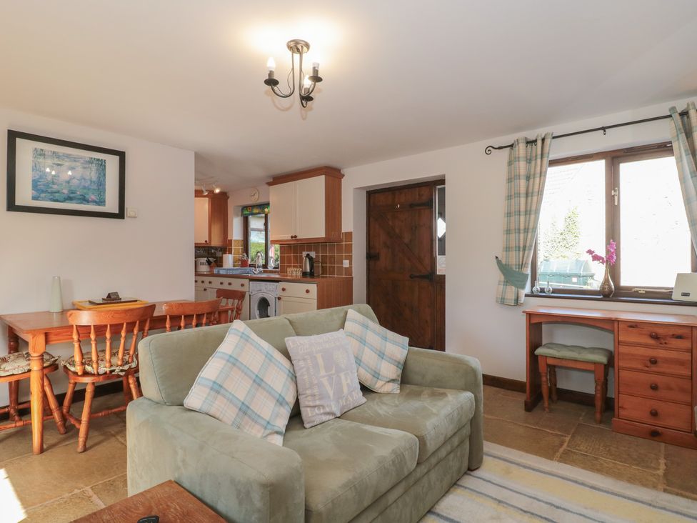 A living room with a sofa and dining area at The Cowshed in Bristol