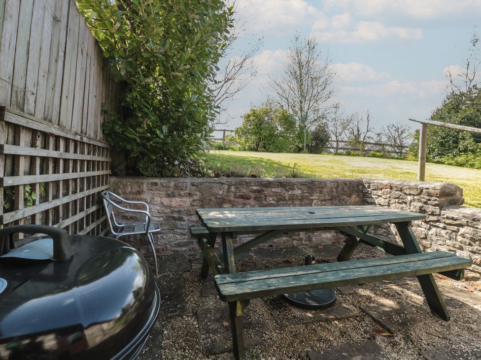 An outdoor area with a picnic table and grill at The Cowshed in Bristol