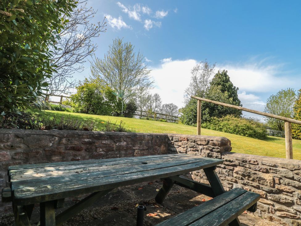 A garden with a stone wall and a picnic table at The Cowshed in Bristol