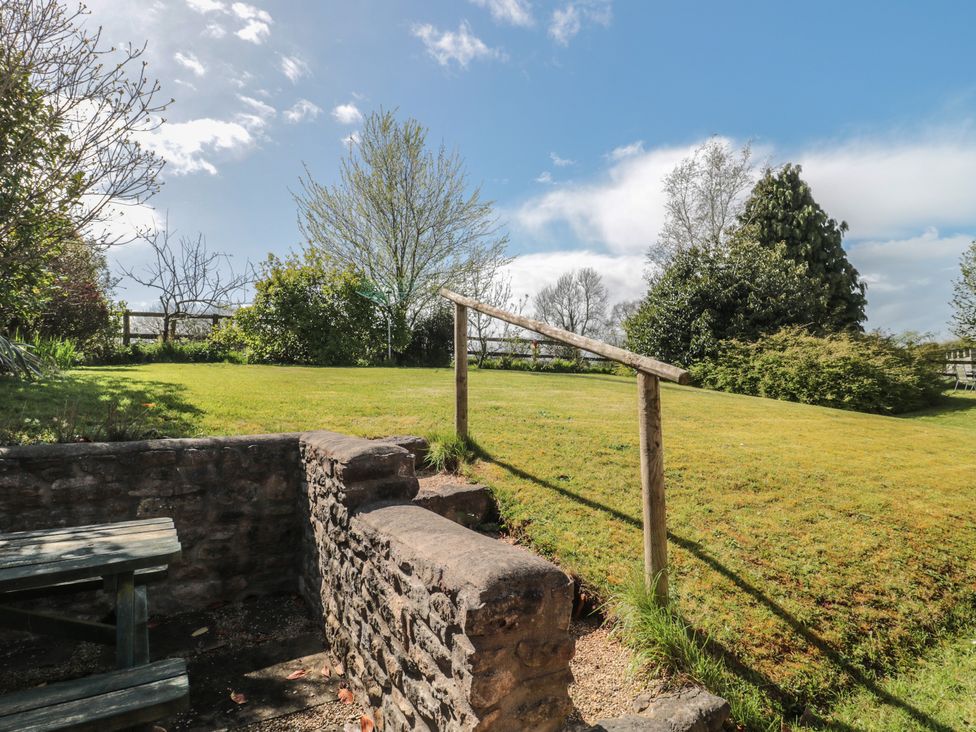 A garden with a stone wall and trees at The Cowshed in Bristol