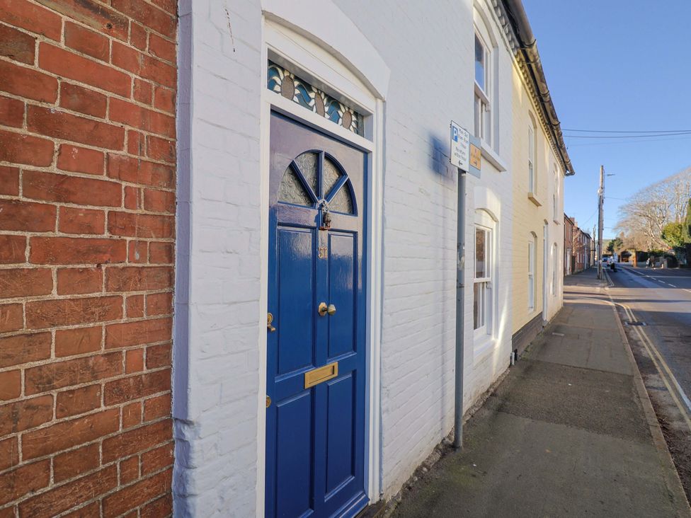 A blue front door next to a brick wall at Rope Cottage in Bridport