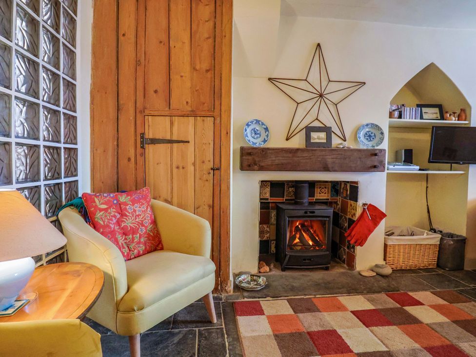 A living room with a fireplace and armchair at Rope Cottage in Bridport