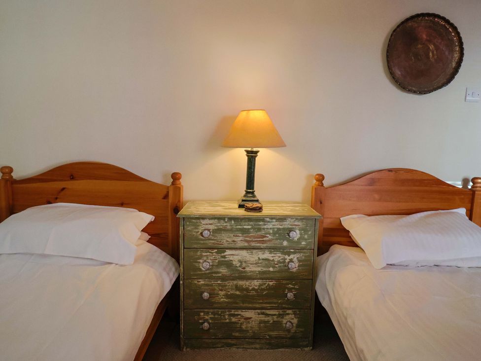 A bedroom with two beds and a green chest of drawers at Rope Cottage in Bridport