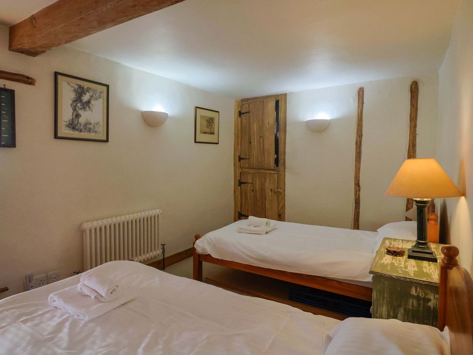 A bedroom with two beds and a table at Rope Cottage in Bridport