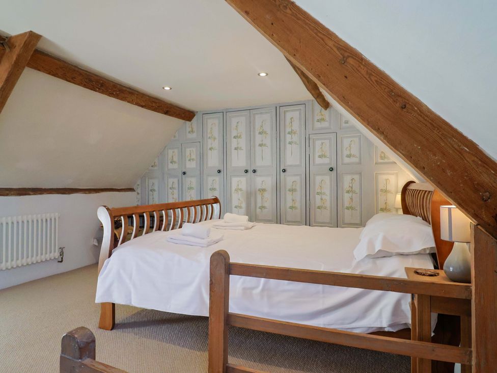 A bedroom with a bed and wardrobe at Rope Cottage in Bridport