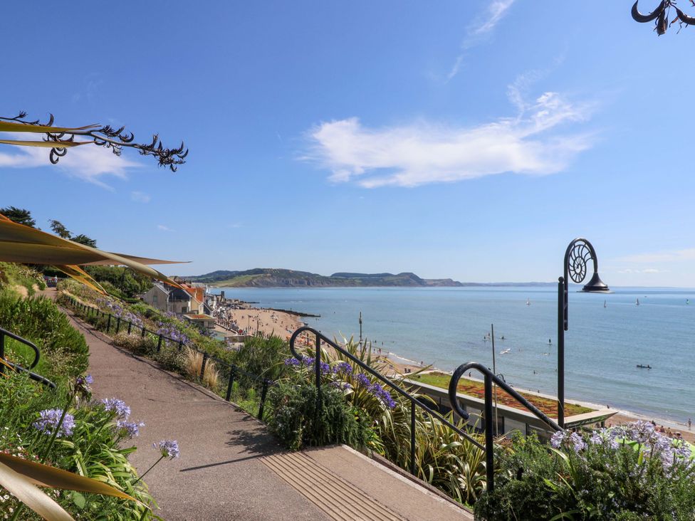 A view of the beach and sea with flowers along the pathway at Rope Cottage Bridport