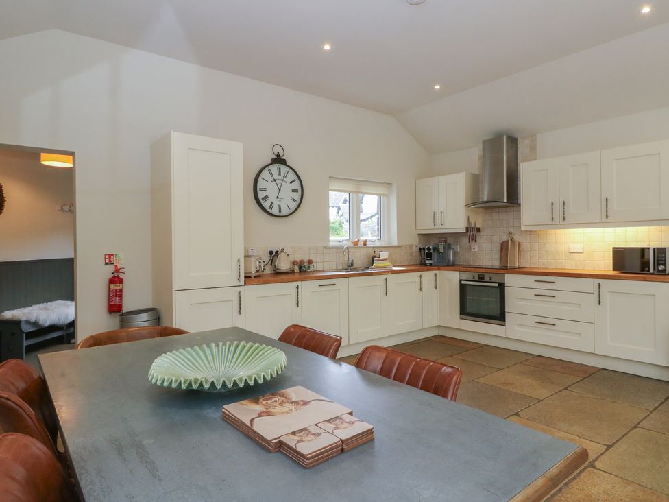 A kitchen with white cabinets and a dining table at Glen Lochay Lodge in Killin