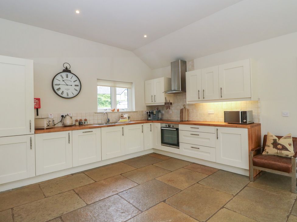 A kitchen with cabinets, appliances, and a clock at Glen Lochay Lodge in Killin