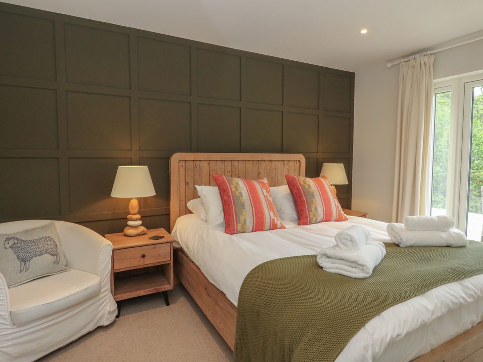 A bedroom with a bed and a chair at Glen Lochay Lodge in Killin