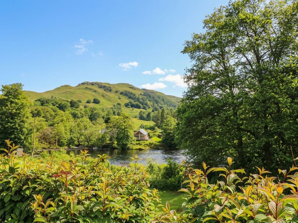 A view of a river with a house and hills at Glen Lochay Lodge in Killin