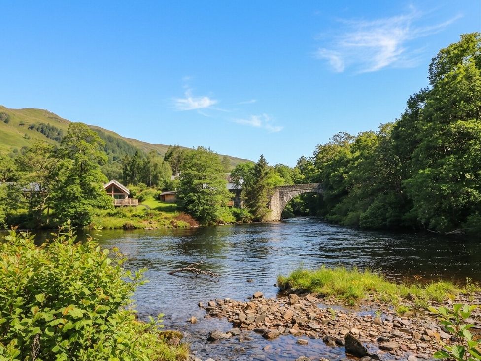 A river with a bridge and trees at Glen Lochay Lodge in Killin