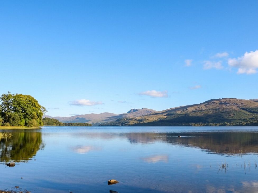 A scenic view of a lake with mountains and trees at Glen Lochay Lodge in Killin