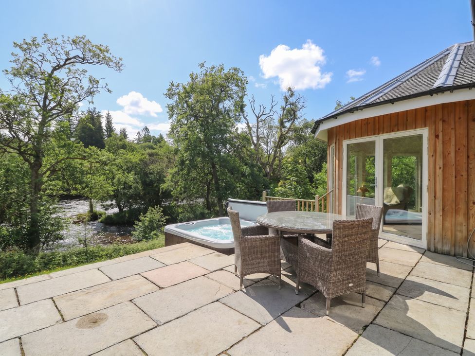 An outdoor area with a hot tub and a table with chairs at Glen Lochay Lodge in Killin
