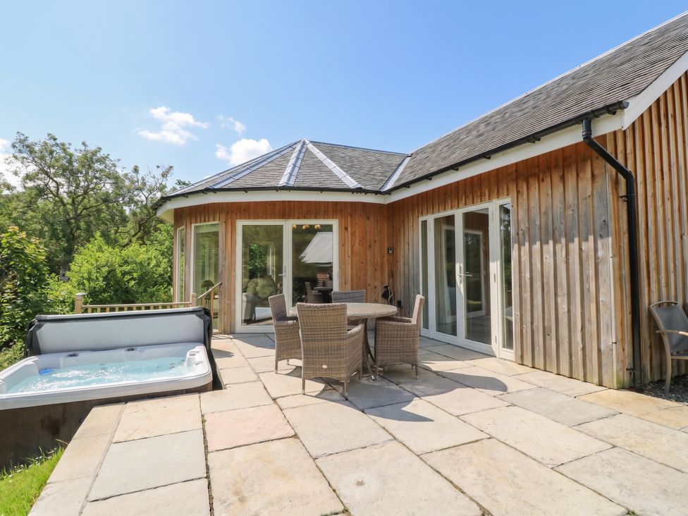 An outdoor area with a table and chairs next to a hot tub at Glen Lochay Lodge in Killin