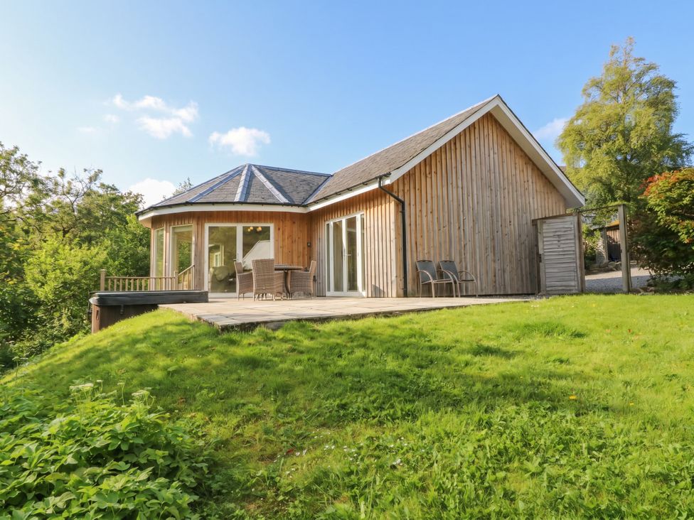 A wooden house with a deck and chairs at Glen Lochay Lodge in Killin