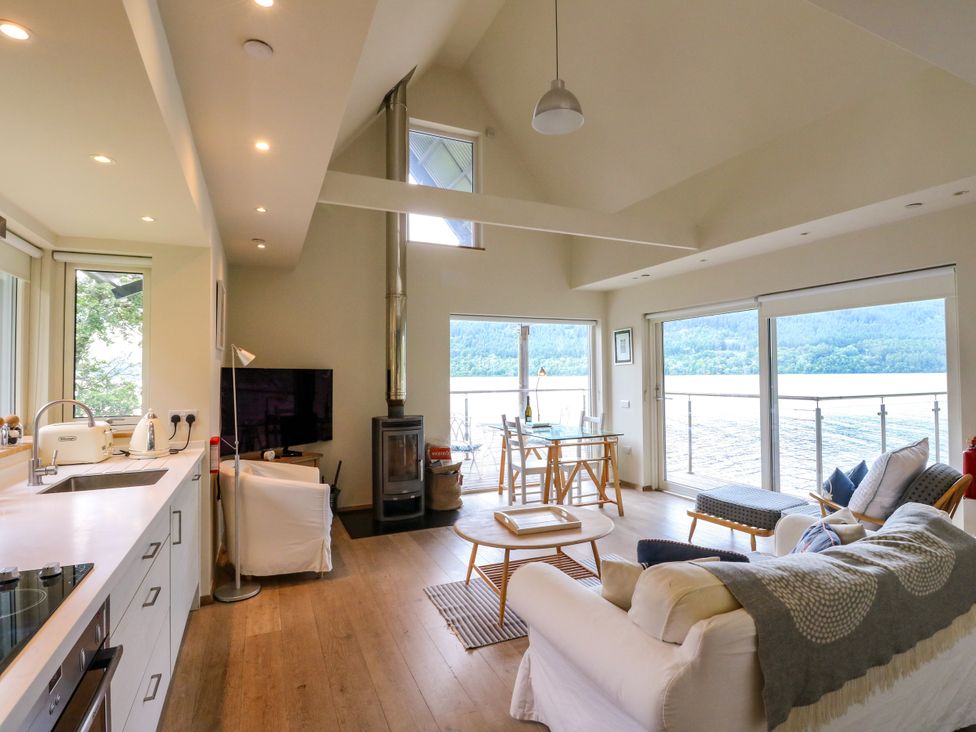 A living room with a sofa and dining table at Osprey Boathouse in Killin