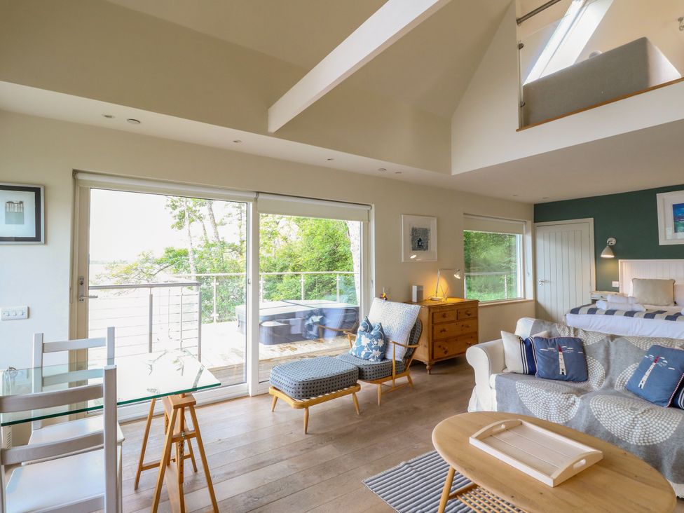 A living room with a sofa, armchair, and dining table at Osprey Boathouse in Killin