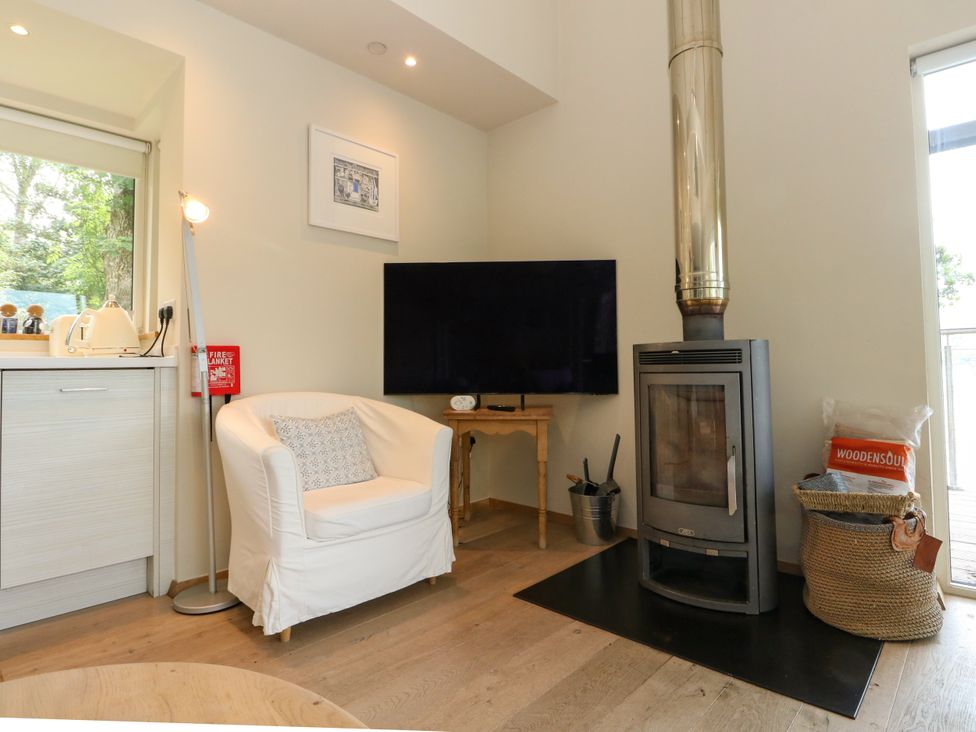 A living room with an armchair and wood stove at Osprey Boathouse in Killin