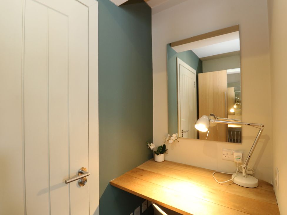 A desk with a lamp and a mirror in an office at Osprey Boathouse in Killin
