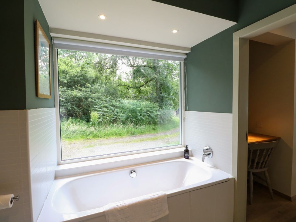 A bathroom featuring a bathtub and a large window at Osprey Boathouse in Killin
