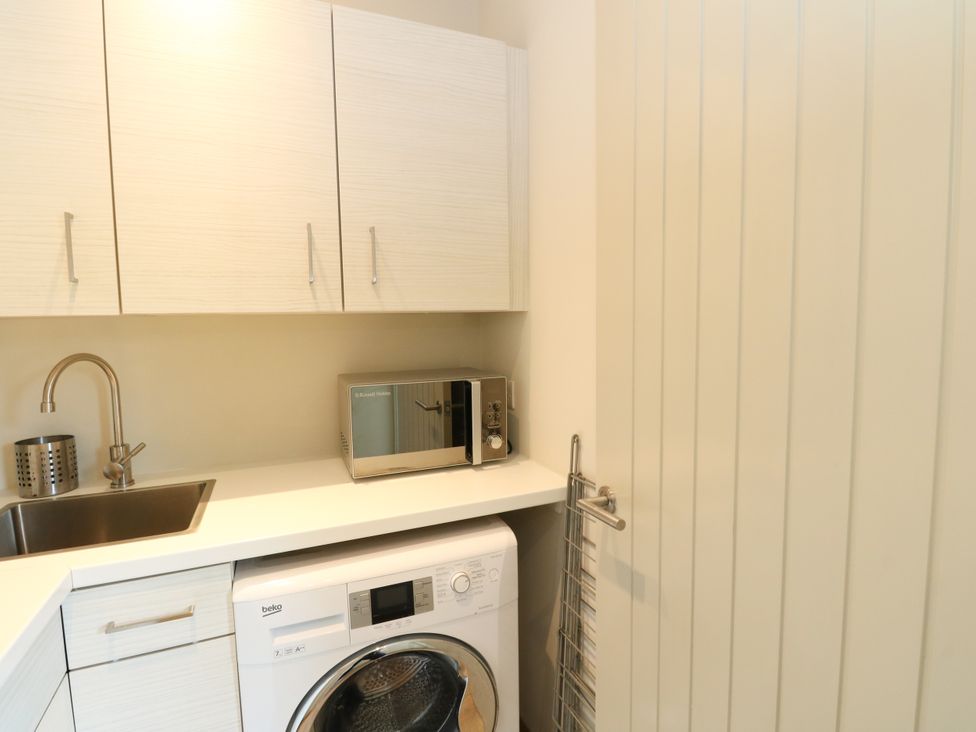 A laundry room with a sink and washing machine at Osprey Boathouse in Killin