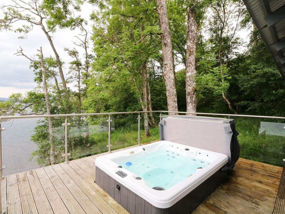 An outdoor space with a hot tub and surrounding trees at Osprey Boathouse in Killin