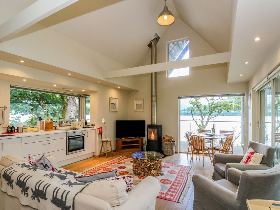 A living room with a kitchen area and seating at Dipper Boathouse in Killin