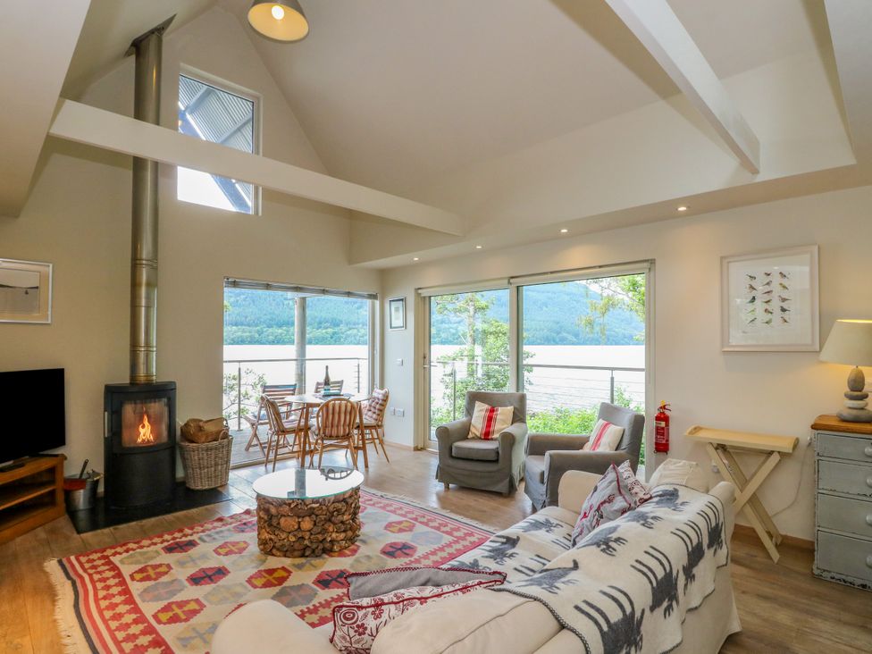 A living room with a sofa, armchairs, and a dining table at Dipper Boathouse in Killin