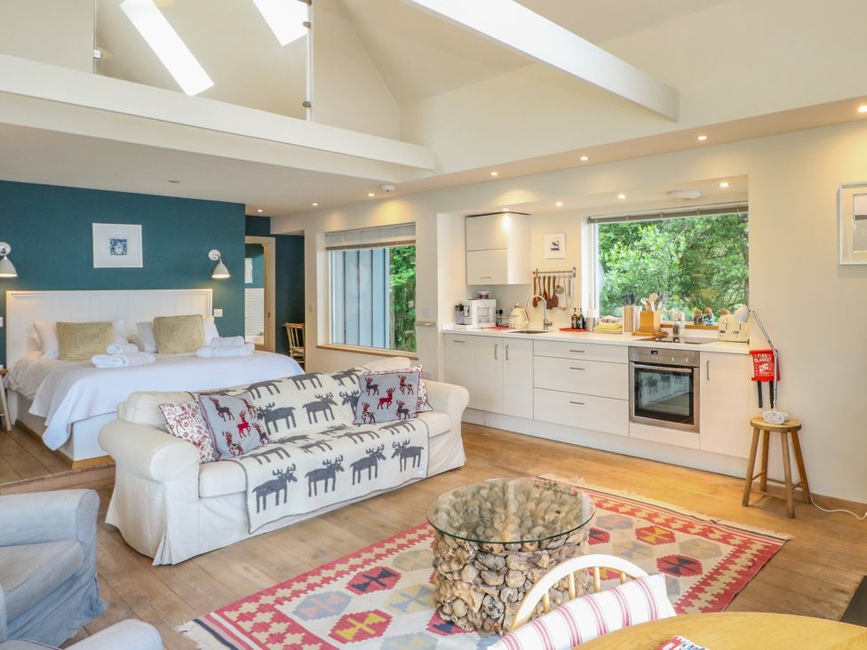 A living room with a kitchen and seating area at Dipper Boathouse in Killin
