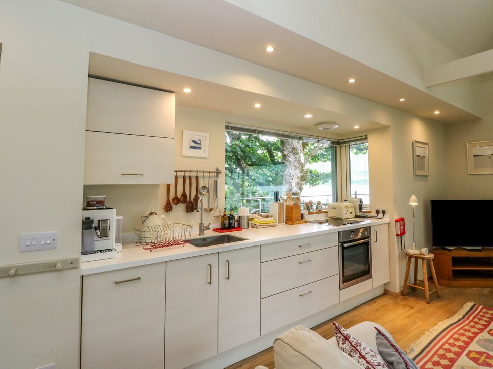 A kitchen with cabinets and a television at Dipper Boathouse in Killin