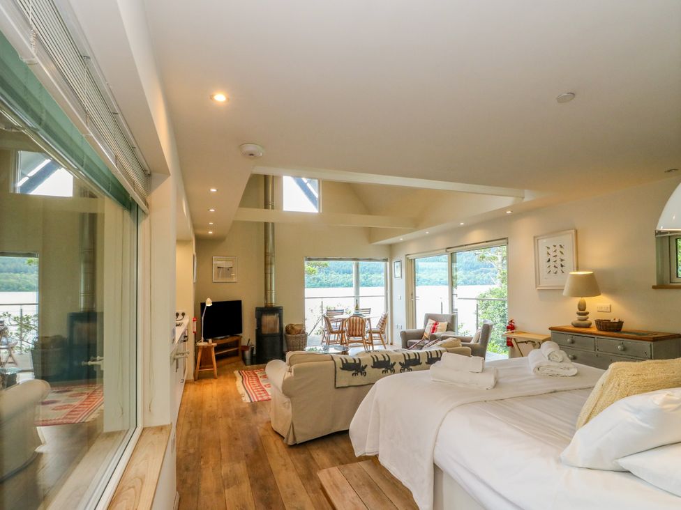 A living room with a sofa and dining table at Dipper Boathouse in Killin