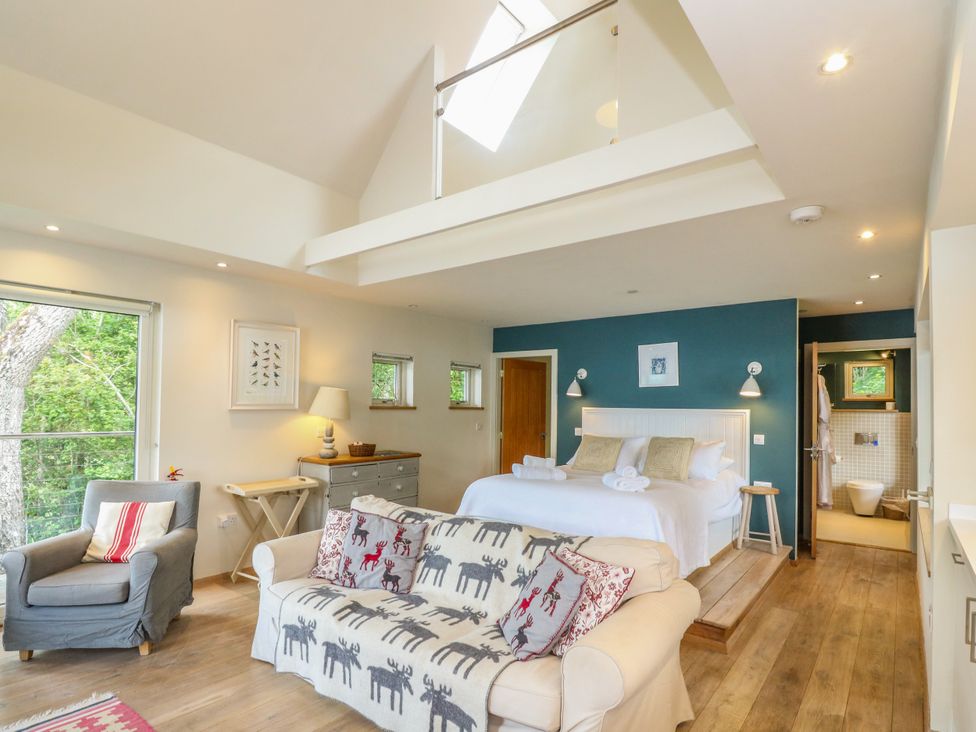 A bedroom with a bed and seating area at Dipper Boathouse in Killin