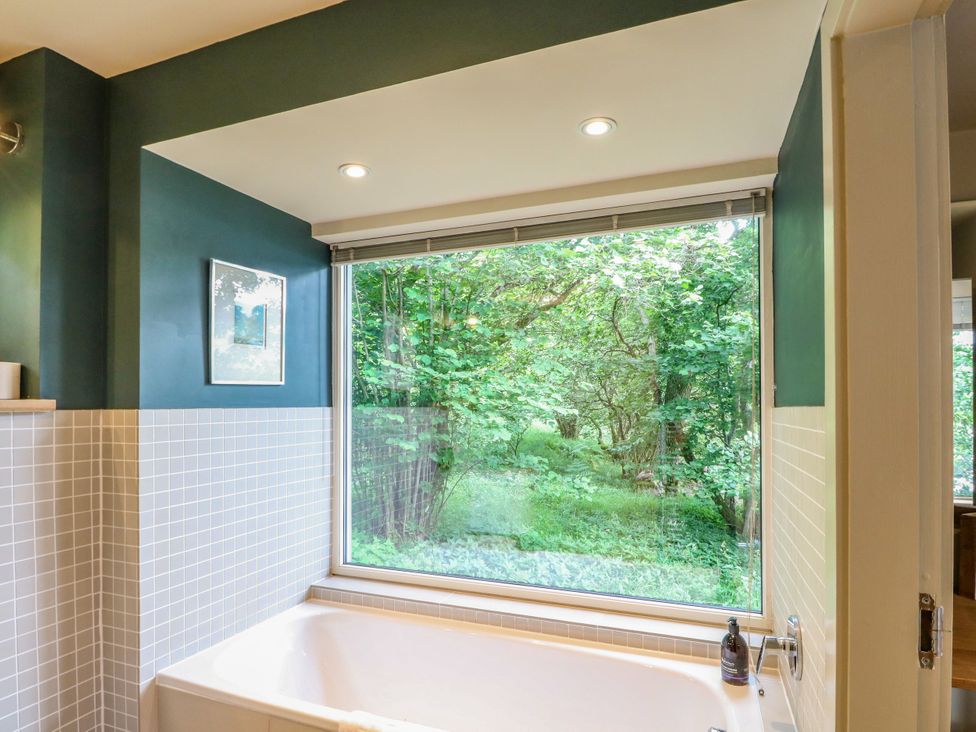 A bathroom with a bathtub and window overlooking greenery at Dipper Boathouse in Killin