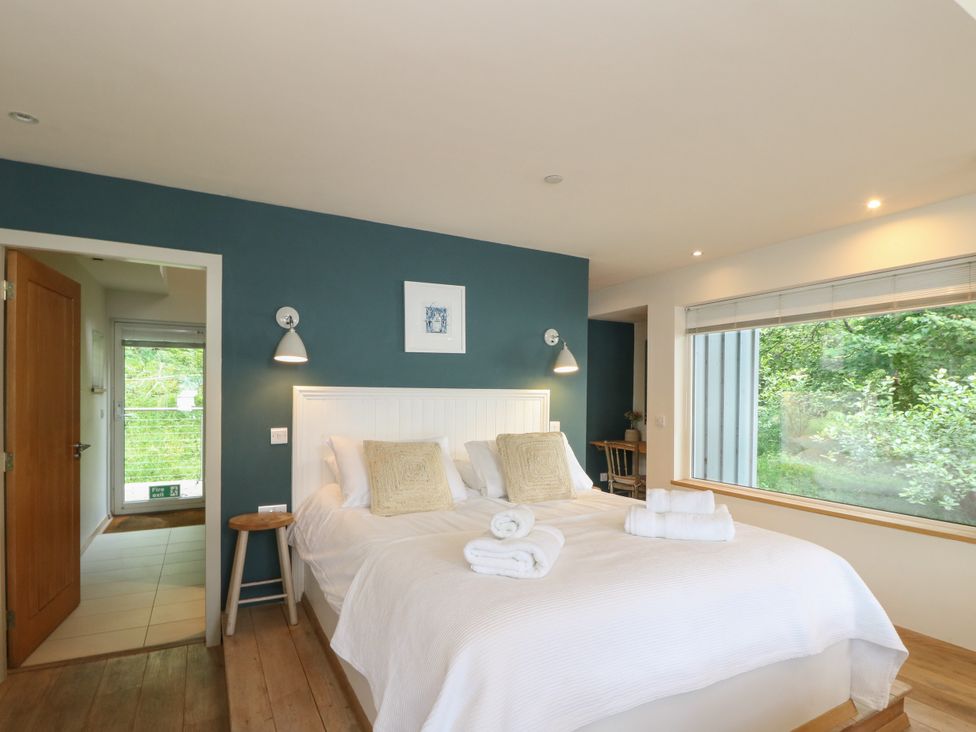 A bedroom with a double bed and entrance to outdoors at Dipper Boathouse in Killin