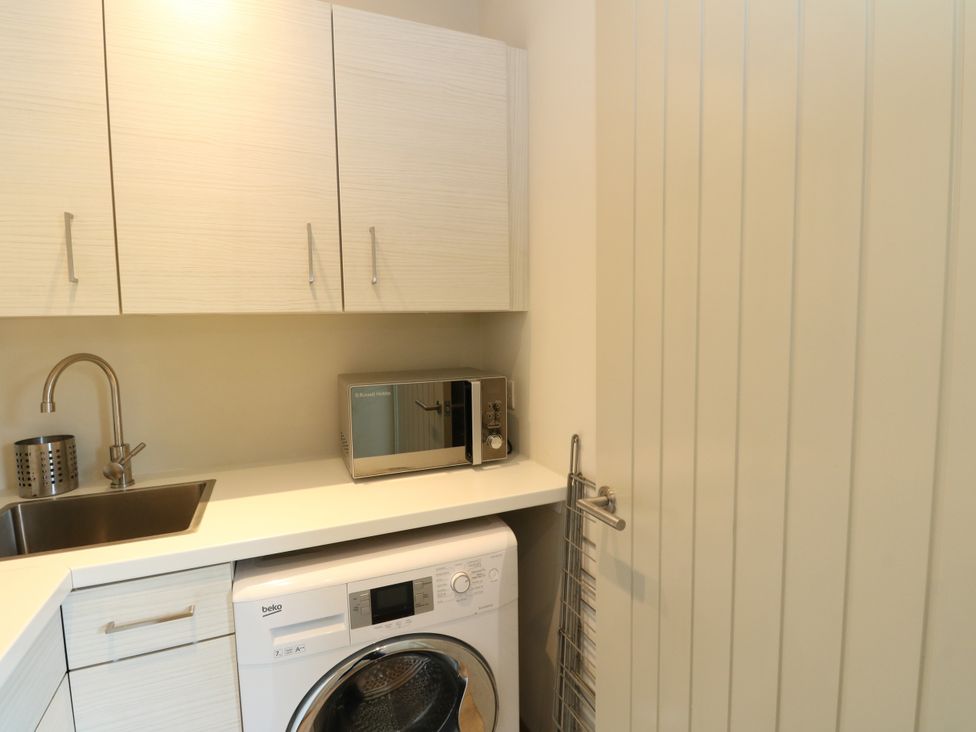 A laundry room with appliances and storage at Dipper Boathouse in Killin