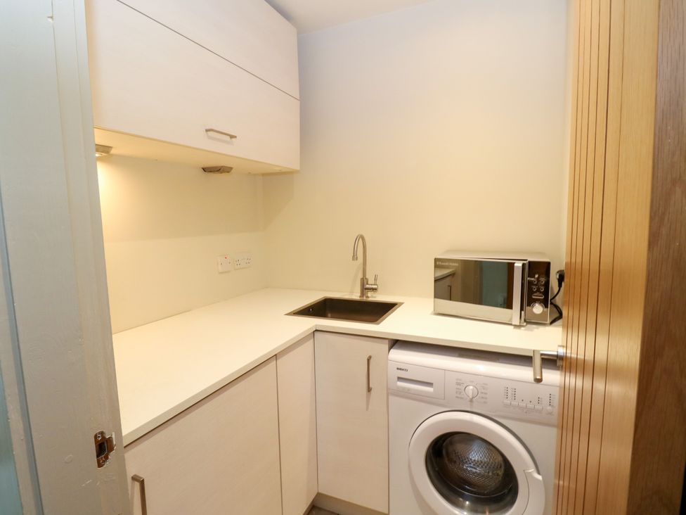 A kitchen with a sink, microwave, and washing machine at Dipper Boathouse in Killin