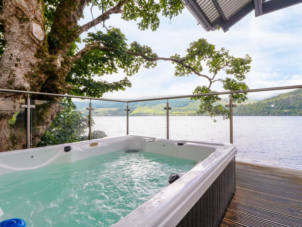 A hot tub on a deck overlooking a lake at Dipper Boathouse in Killin