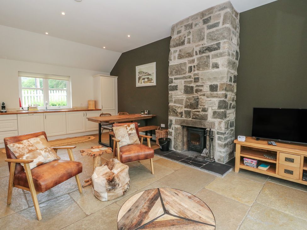 A living room with a stone fireplace and chairs at Ghillie's Cottage in Killin