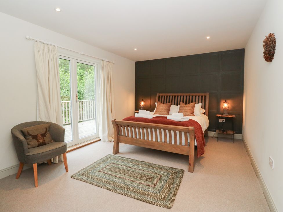 A bedroom with a bed and armchair at Ghillie's Cottage in Killin
