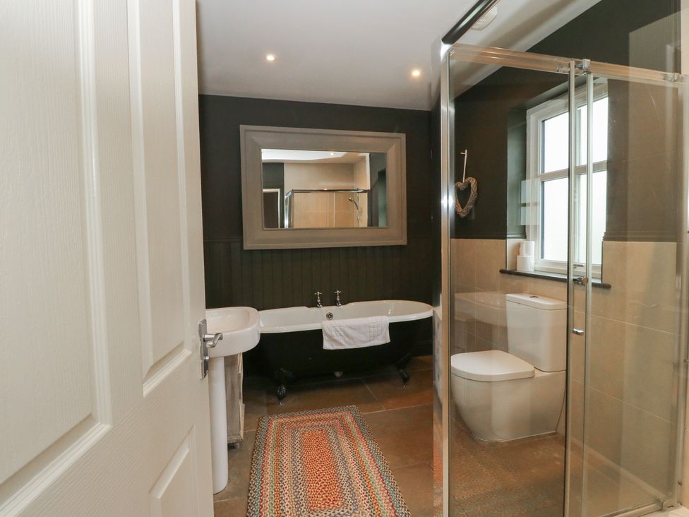A bathroom with a bathtub, shower, toilet, and sink at Ghillie's Cottage in Killin