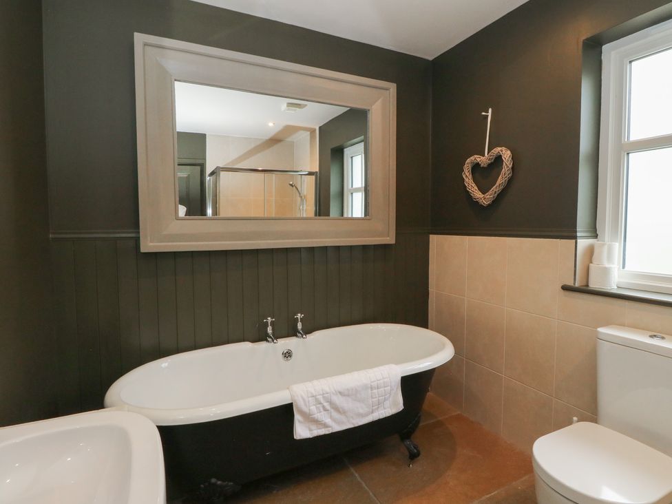 A bathroom with a bathtub, toilet, and mirror at Ghillie's Cottage in Killin